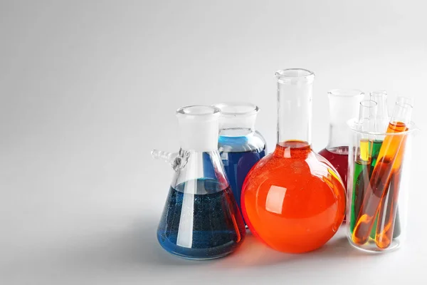 Chemical glassware with colorful liquids on light background — Stock Photo, Image