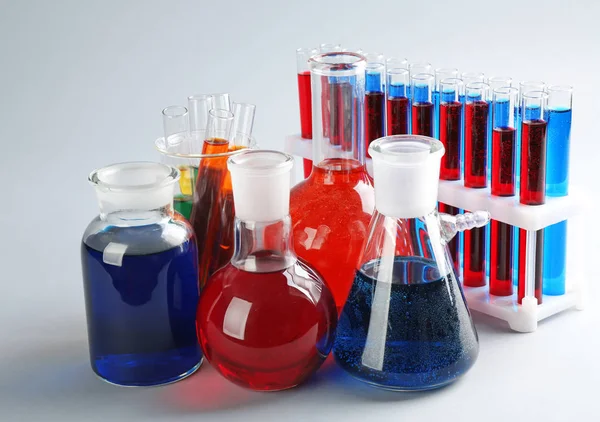 Χημική γυαλικών με πολύχρωμα υγρά επάνω ελαφρύς υπόβαθρο — Φωτογραφία Αρχείου