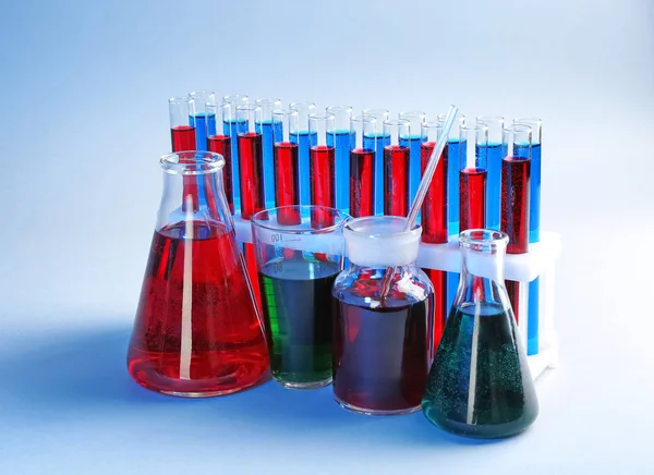 Chemical glassware with different liquids on color background — Stock Photo, Image