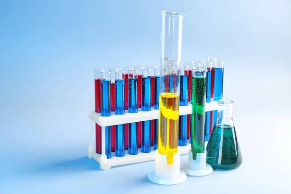 Chemical glassware with different liquids on color background — Stock Photo, Image