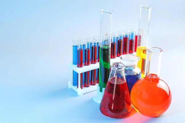 Chemical glassware with different liquids on color background — Stock Photo, Image