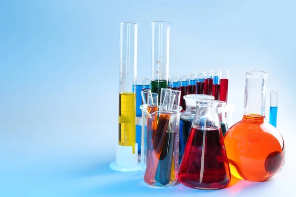 Chemical glassware with different liquids on color background — Stock Photo, Image