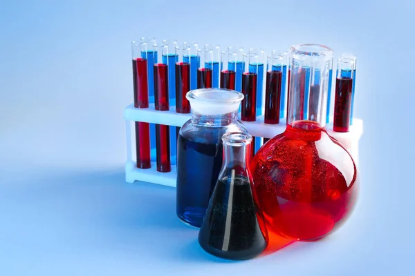 Vetreria chimica con diversi liquidi su sfondo colore — Foto Stock