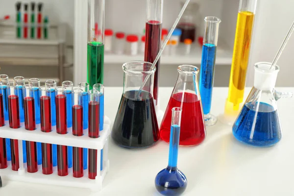 Chemische glaswerk met kleurrijke vloeistoffen op tafel — Stockfoto