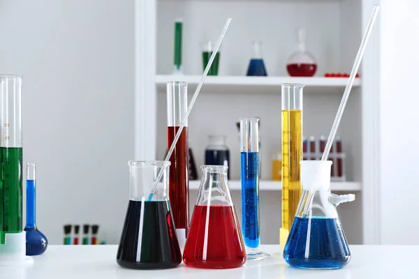 Chemiegläser mit bunten Flüssigkeiten auf dem Tisch — Stockfoto