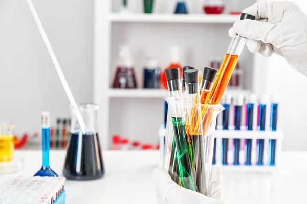 Lab worker holding beaker with test tubes on blurred background