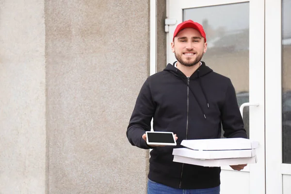 Jonge man met kartonnen pizzadozen en tablet buitenshuis. Levering foodservice — Stockfoto