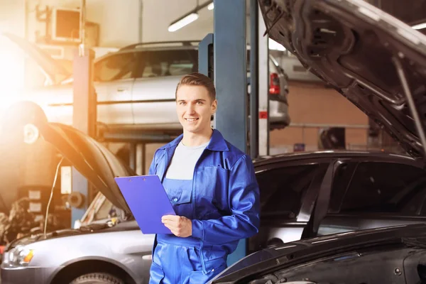 Male mechanic with clipboard near car in service center Royalty Free Stock Photos