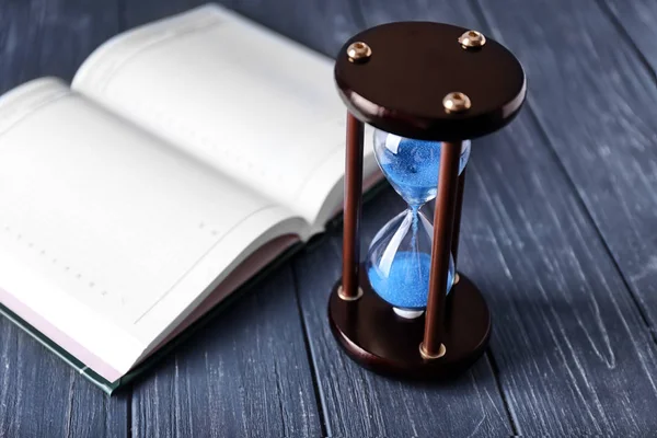 Stylish hourglass and notebook on table. Time management concept Stock Picture