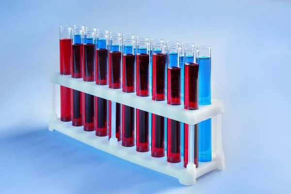 Test tubes with different liquids in holder on color background Royalty Free Stock Images