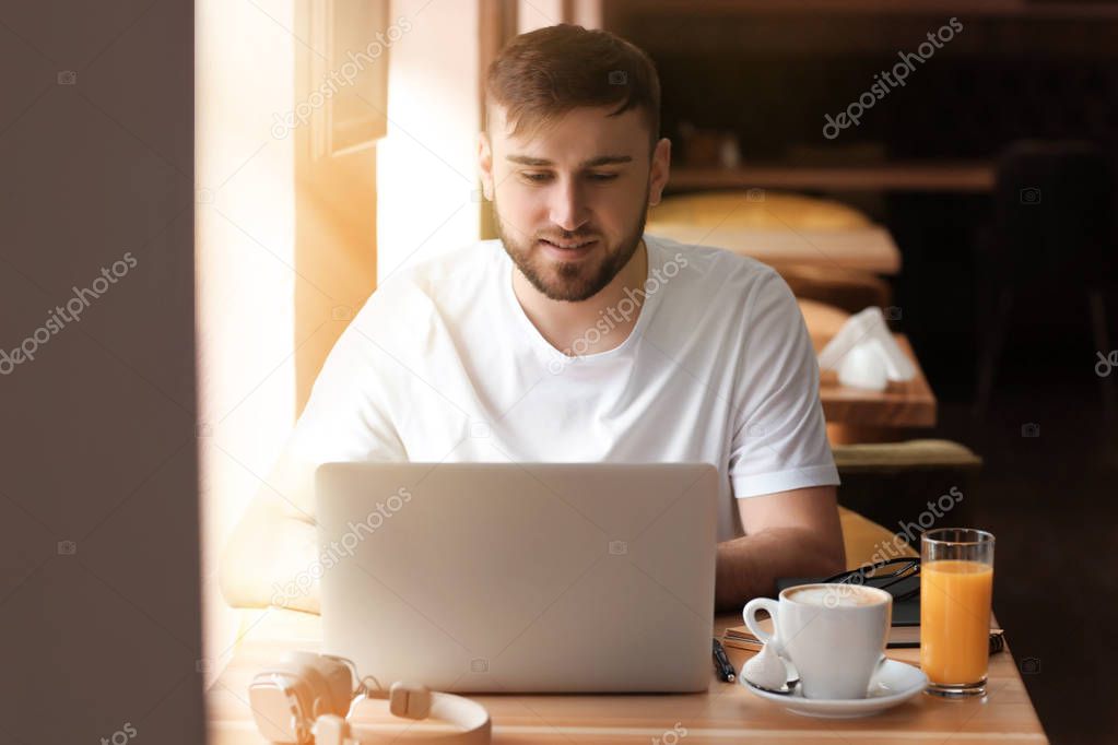 Young freelancer with laptop working in cafe