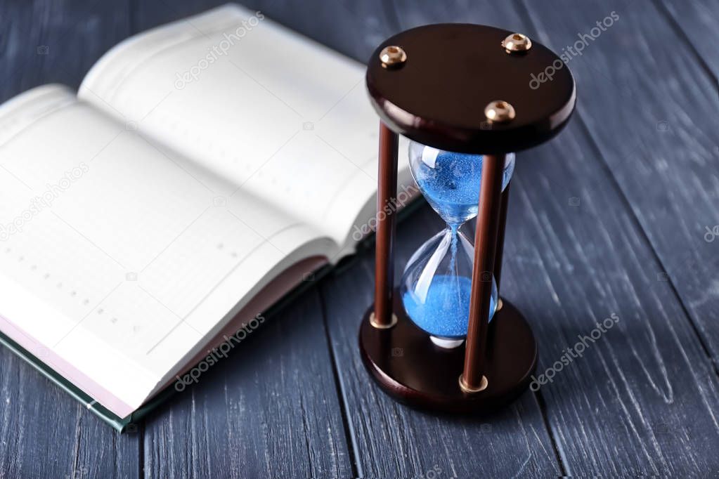 Stylish hourglass and notebook on table. Time management concept