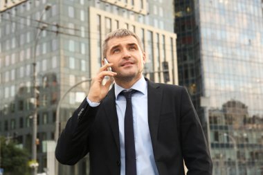 Dışarıda cep telefonuyla konuşan yakışıklı bir iş adamı.