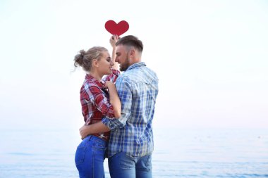 Sevimli genç bir çift deniz kıyısında kırmızı kalpli