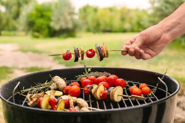 Sebzeli şiş açık havada barbekü ızgara üzerinde tutan adam