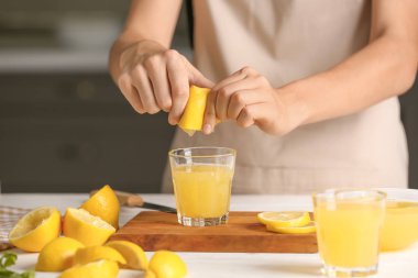 Kadın masada cam içine taze limon suyu sıkma