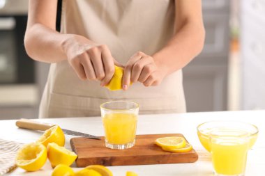 Kadın masada cam içine taze limon suyu sıkma