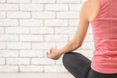 Beyaz tuğla zemin üzerine meditasyon sportif genç kadın