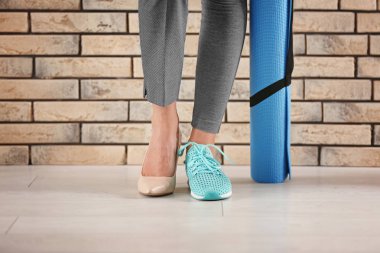 Yüksek topuklu ayakkabı ve tuğla duvar yakınındaki spor ayakkabı giyen genç kadın. Geri kalan çalışma arasındaki denge kavramı