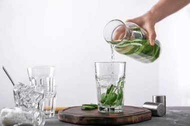 Kadın lezzetli taze salatalık su şişe açık renkli cam içine dökme