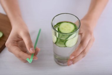 Lezzetli taze salatalık suyu ve saman ile cam masa lambası tutan kadın