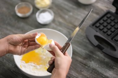 Ahşap masa üzerinde lezzetli waffle, hazırlanması için hamur yapma kadın