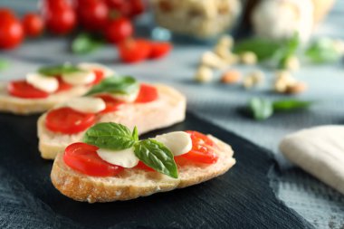 Domates, Yeşil fesleğen ve mozarella peyniri kayrak plaka üzerinde taze ekmek