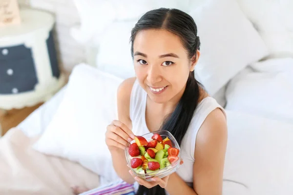 Asian woman eating healthy fruit salad at home — Stock Photo, Image