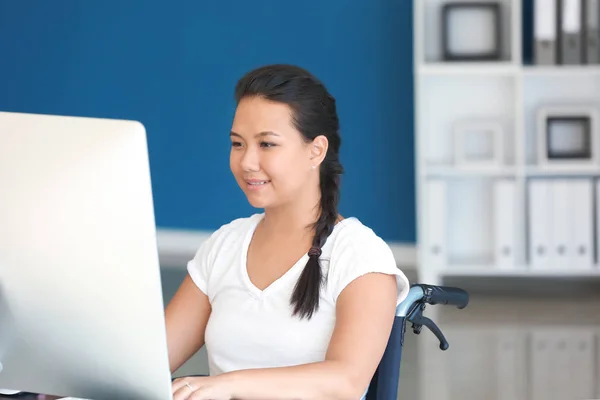 Asiatisk kvinna i rullstol som arbetar med dator i office — Stockfoto