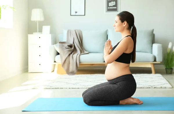 Joven embarazada practicando yoga en casa — Foto de Stock