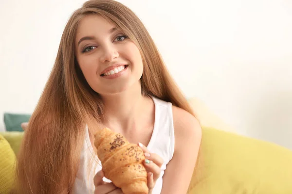 Женщина ест вкусный круассан в спальне — стоковое фото
