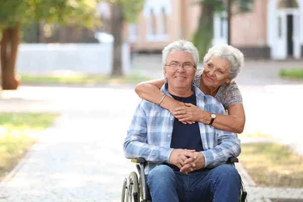 Happy senior man in wheelchair and his wife outdoors — Stock Photo, Image