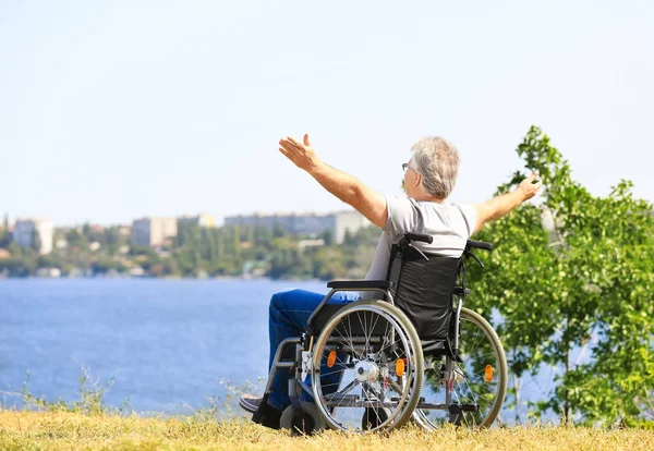 Happy senior man in wheelchair near river — Stock Photo, Image