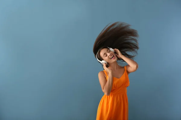 Vacker ung kvinna lyssnar på musik på färg bakgrund — Stockfoto