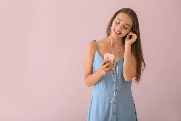 Beautiful young woman listening to music on color background — Stock Photo, Image