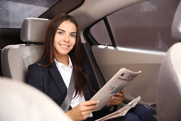 Молода бізнес-леді читає газету в машині — стокове фото