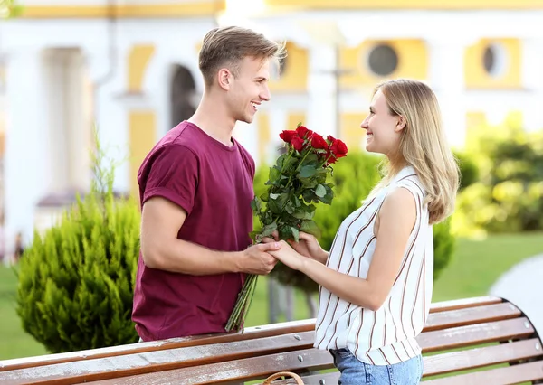 Jeune homme donnant des fleurs à sa petite amie sur la date romantique en plein air — Photo