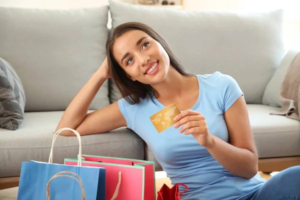 Gelukkig jonge vrouw met boodschappentassen en credit card thuis — Stockfoto