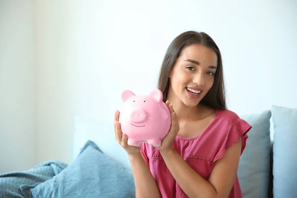 Młoda kobieta z piggy bank w domu — Zdjęcie stockowe