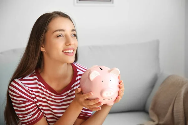 Young woman with piggy bank at home — Stock Photo, Image