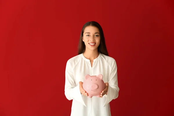 Mujer joven con alcancía sobre fondo de color —  Fotos de Stock