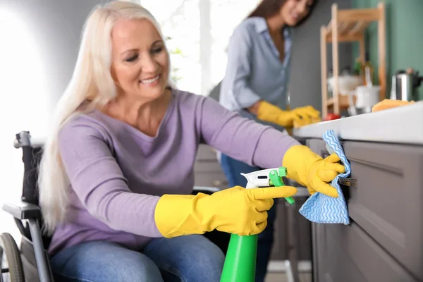 Mulher madura na cozinha de limpeza de cadeira de rodas — Fotografia de Stock