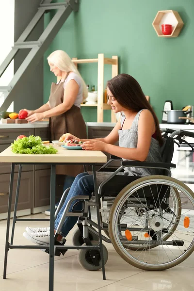 Mladá žena v invalidním vozíku jí doma — Stock fotografie