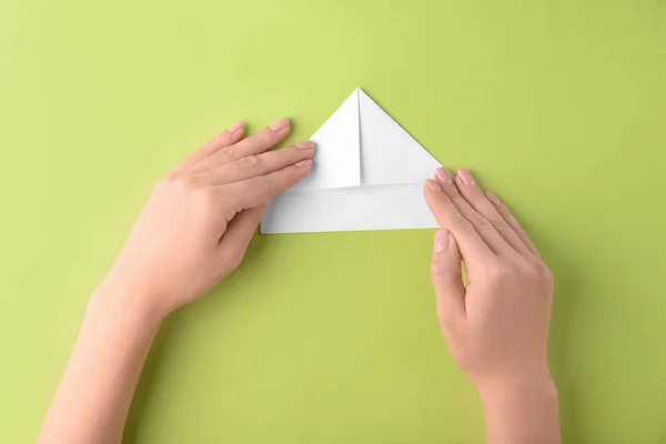 Mulher fazendo origami barco no fundo de cor — Fotografia de Stock