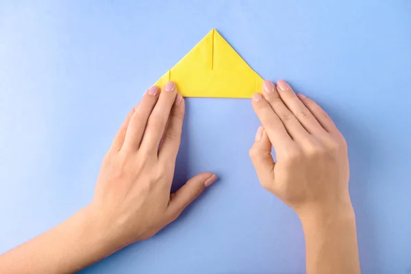 Γυναίκα κάνει origami σκάφος στο χρώμα φόντου — Φωτογραφία Αρχείου