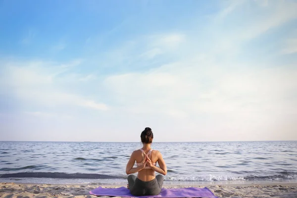 Woman practicing yoga on sea shore — Stock Photo, Image