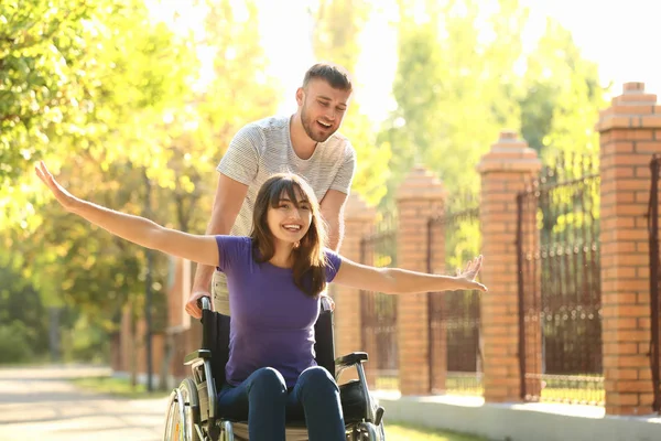 Joyeux jeune femme en fauteuil roulant et son mari à l'extérieur — Photo