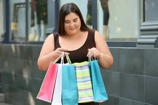 Overgewicht vrouw met boodschappentassen in de buurt van kledingwinkel op straat — Stockfoto