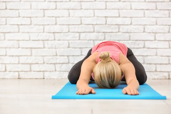 Sportig ung kvinna utövar yoga på matta inomhus — Stockfoto