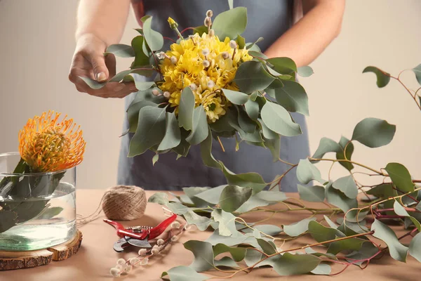 Female florist making beautiful bouquet with chrysanthemum flowers and eucalyptus